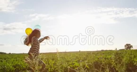 带着气球跑小女孩在绿野里慢镜头背光视频的预览图