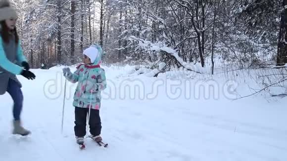 女孩正在学习滑雪她在松软的雪地里慢慢地滑上滑雪板冬天森林里美丽的一天妇女视频的预览图