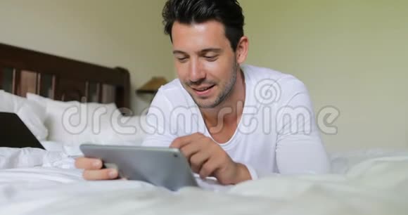 使用平板电脑躺在床上的年轻人在卧室的早晨在网上聊天视频的预览图