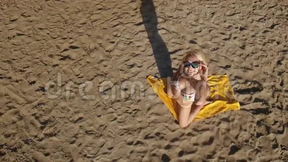 穿比基尼的金发美女在海滩上摆姿势拍照视频的预览图