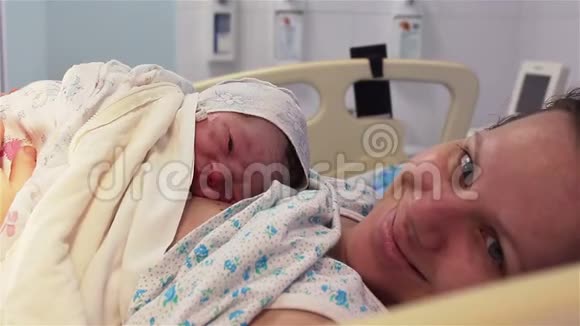 一个新生婴儿躺在医院里一位幸福的母亲的乳房上人生的第一分钟视频的预览图