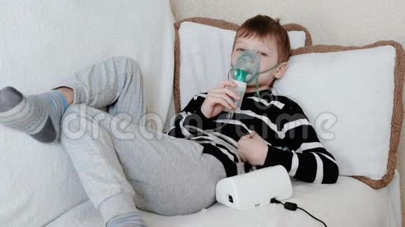 使用雾化器和吸入器进行治疗躺在沙发上的男孩通过吸入器面罩吸入视频的预览图