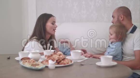 年轻的爸爸妈妈和两个小儿子在茶几上玩得很开心视频的预览图