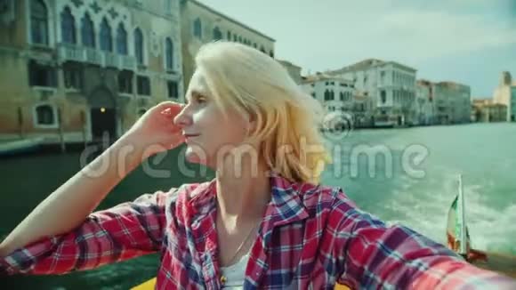 女人正在威尼斯运河上的建筑物背景下拍摄自己意大利旅游业视频的预览图