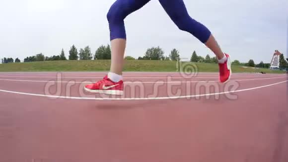 一名穿红色短裙的年轻女子在城市体育场馆的一天跑步训练中跑过镜头视频的预览图