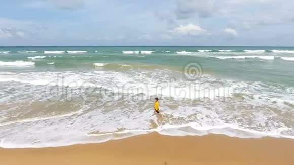 4k空中镜头男孩在热带海域与海滩海浪嬉戏视频的预览图