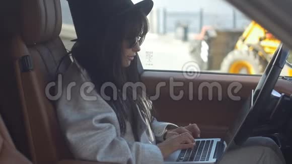 时尚女孩在车里用笔记本电脑视频的预览图