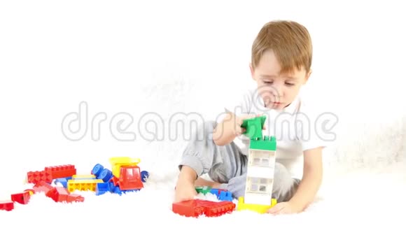 快乐的孩子在彩色的积木里玩耍坐在白色的背景上运动相机滑块视频的预览图