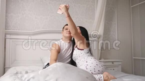 幸福快乐的情侣在床上自拍年轻迷人的男女穿着睡衣视频的预览图