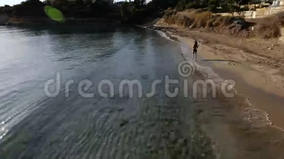 美丽的黑发女郎沿着海边奔跑视频的预览图