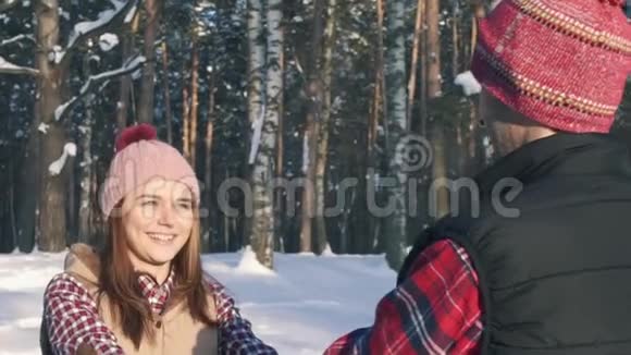 女孩带着一个年轻人微笑走在冬天的森林里阳光明媚的一天视频的预览图