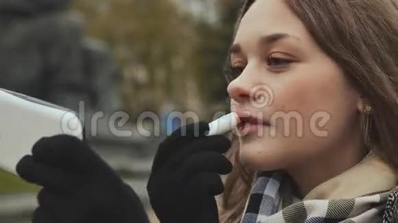 这位年轻漂亮的女孩用口红在她的嘴唇上涂上卫生的秋天时光快关门视频的预览图