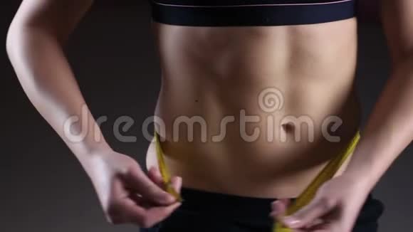 活动妇女展示平坦的腹部用胶带测量腰部减肥视频的预览图