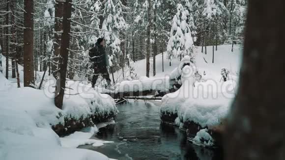 冬天的那天一个年轻人站在河边的雪覆盖的小径上视频的预览图
