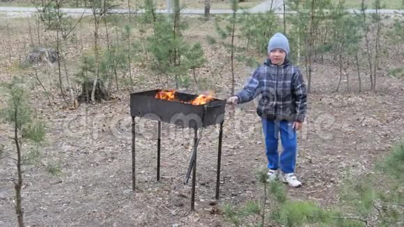 男孩在烤架里生火做饭乡村休息视频的预览图