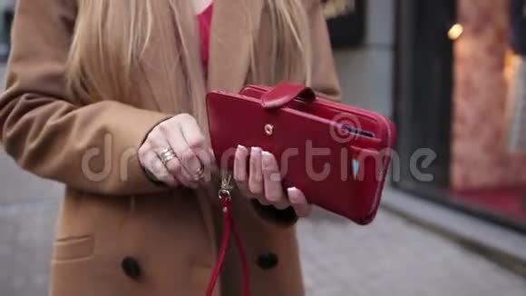 优雅的女人在户外打开红色钱包视频的预览图