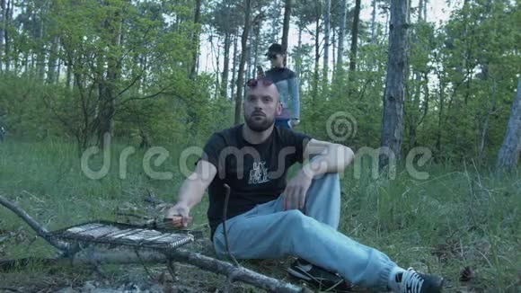 一对年轻夫妇正在城外的树林里休息一个年轻人正在木桩旁准备晚餐一个漂亮的女人视频的预览图
