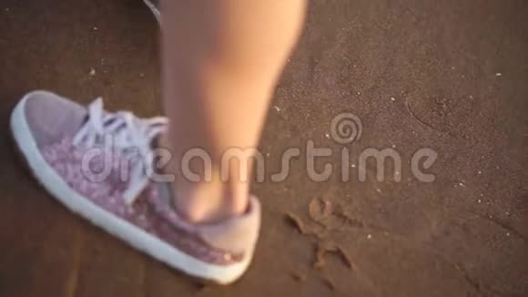 一个穿着运动鞋女孩的腿在海滩上行走的特写镜头视频的预览图