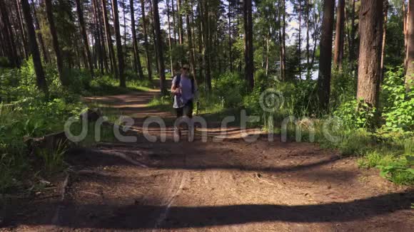 女徒步旅行者带着背包和北欧两极在森林的小路上视频的预览图