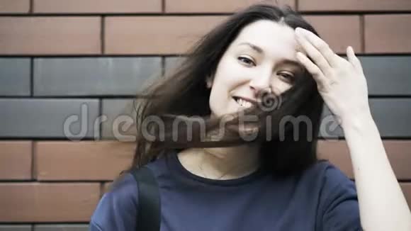 一位年轻女子拿着老式相机靠近砖墙关上视频的预览图