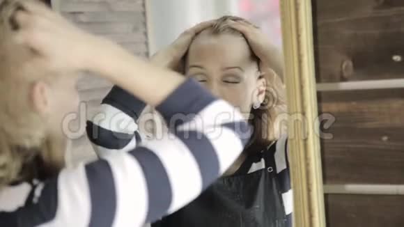 美丽的女人闭上眼睛在镜子前按摩她的头视频的预览图