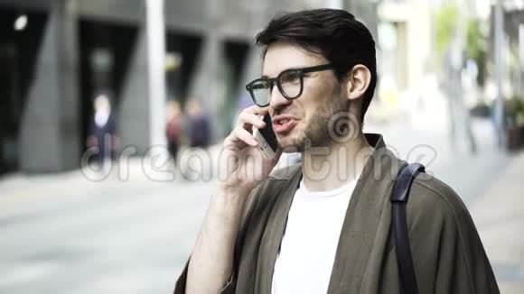 关上一个戴眼镜的时髦男人在电话里说话在外面笑视频的预览图