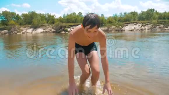 少年抚摸着一个湿漉漉的近水河的慢动作视频夏天在海滩洗澡的少年视频的预览图