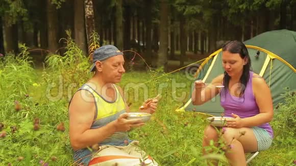 男人和女人在森林里的帐篷附近吃水果沙拉视频的预览图
