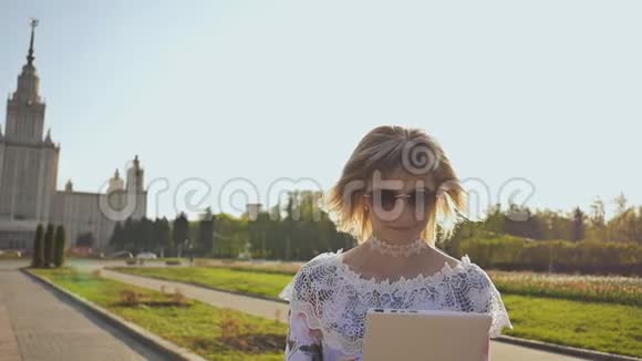年轻女孩使用平板电脑户外和微笑女孩在公园里使用数字平板电脑学生放学后使用平板电脑视频的预览图