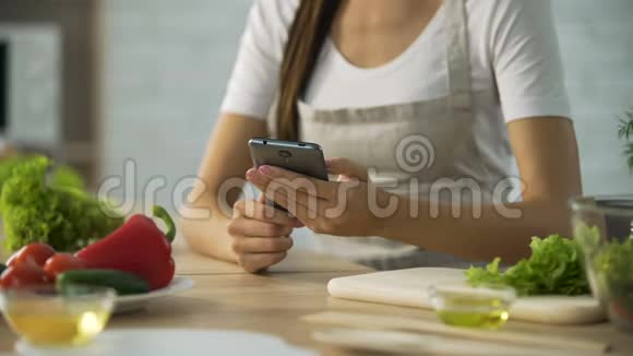 女人在厨房的智能手机上选择沙拉食谱烹饪应用视频的预览图