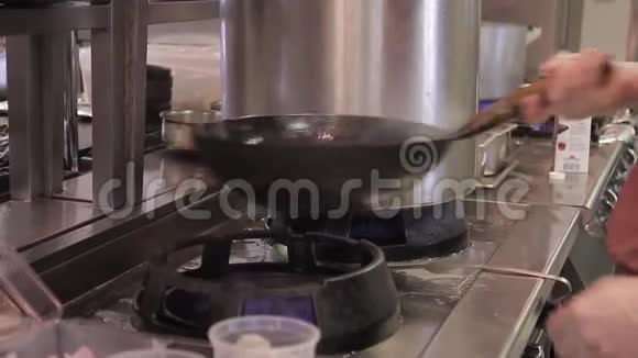 厨师把原料混合在空气中的炒锅里在厨房里烤火视频的预览图