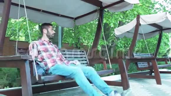 一个年轻人在一个木制沙发上摇摆那个人休息了一下视频的预览图