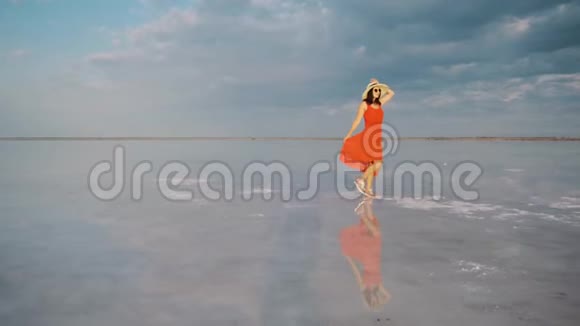 游客穿着一件挥舞着的衣服沿着一个天空反射的盐湖散步视频的预览图