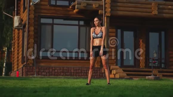 一位身材苗条穿着运动服的美女正准备在她附近的草坪上开始训练视频的预览图