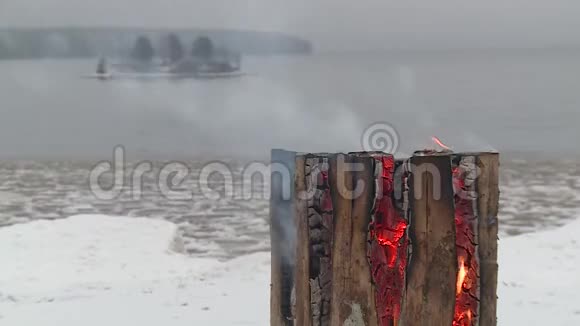 冬天湖岸的原木燃烧视频的预览图