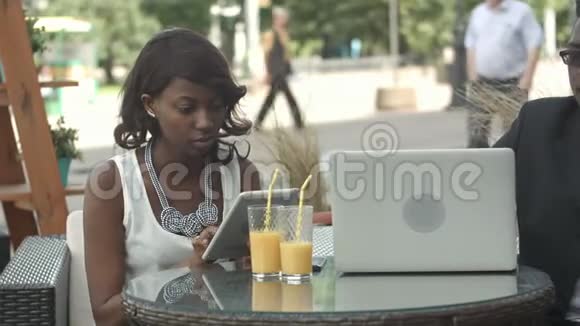 美国黑人商业男女在现代咖啡馆工作打电话使用笔记本电脑和数字视频的预览图