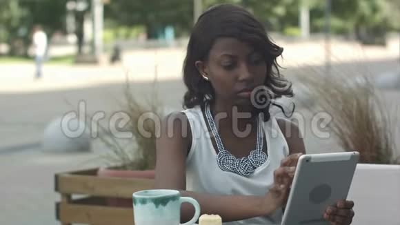 在户外咖啡馆工作和使用平板电脑的非洲年轻商务女性视频的预览图