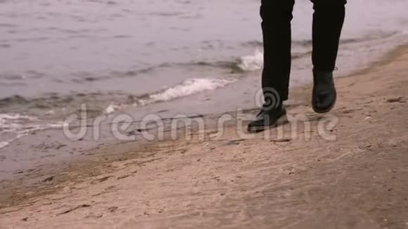 一个穿着西装黑鞋的人沿着大海走视频的预览图