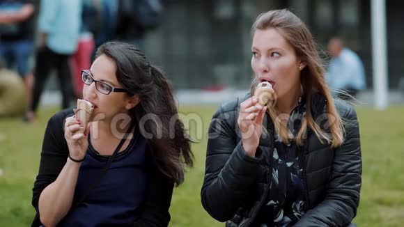 两个女孩坐在公园的草地上吃冰淇淋视频的预览图