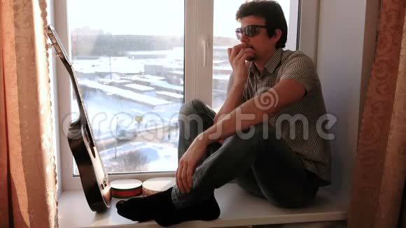 演奏乐器男人坐在窗台上玩口风琴视频的预览图