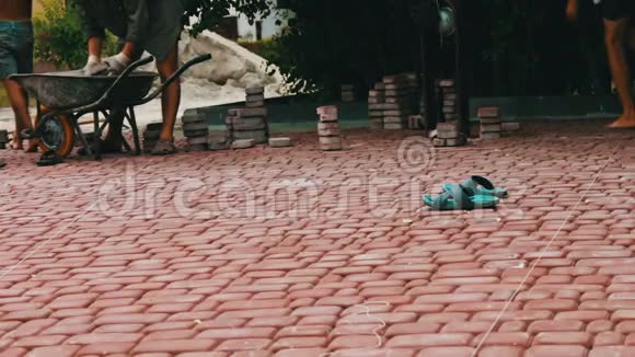 男子在一个儿童公园里铺设装饰五彩铺路砖修理人行道工人铺石板视频的预览图