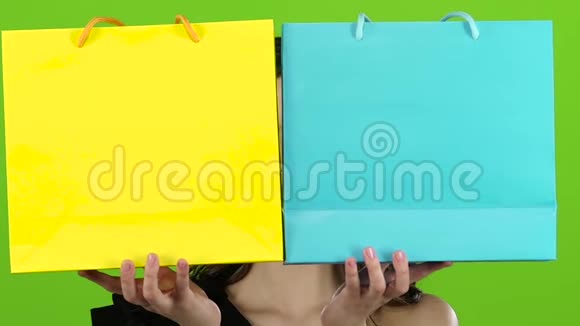 女孩用两个包关闭脸从背后窥视并隐藏绿色屏幕快关门慢动作视频的预览图