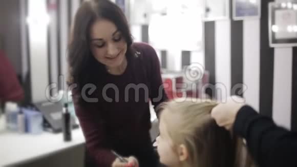 小女孩是一个坐在椅子上的客户她是一个理发师和化妆师视频的预览图