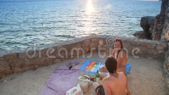 可爱的一对夫妇在日落时在海滩上吃零食视频的预览图