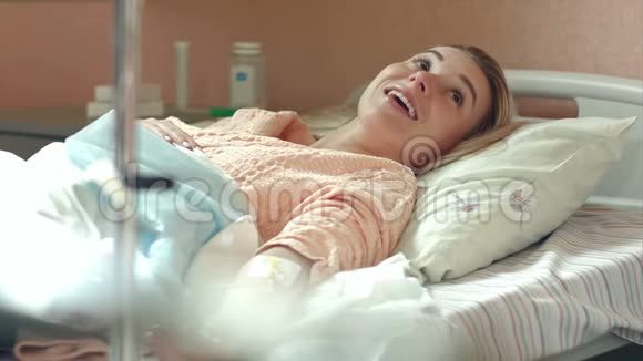 躺在医院病床上的年轻女性病人在与医生交谈时点滴视频的预览图