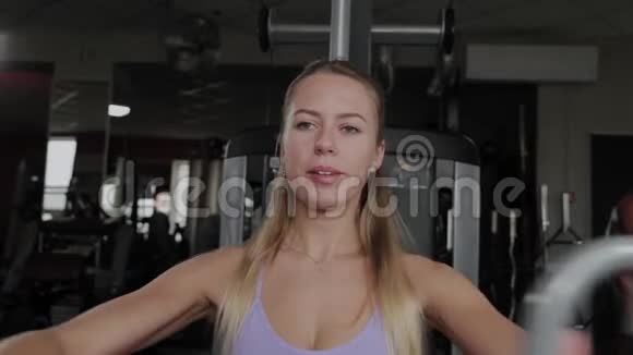 一个身材漂亮的运动女性在健身房的模拟器上训练胸肌视频的预览图
