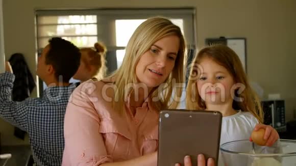 母亲和女儿在准备食物时使用数码平板电脑视频的预览图