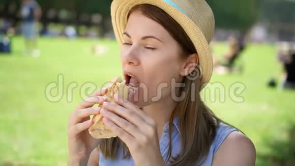 饥饿的女人在公园里吃面包游客在公共公园享用午餐享受夏日阳光视频的预览图