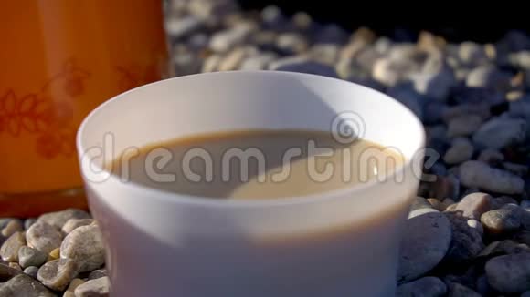 在海滩上把咖啡和牛奶倒入杯子里视频的预览图