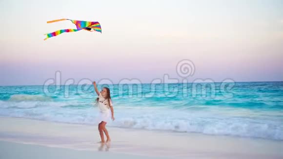 可爱的小女孩在热带海滩放风筝孩子在海边玩美丽的日落视频的预览图